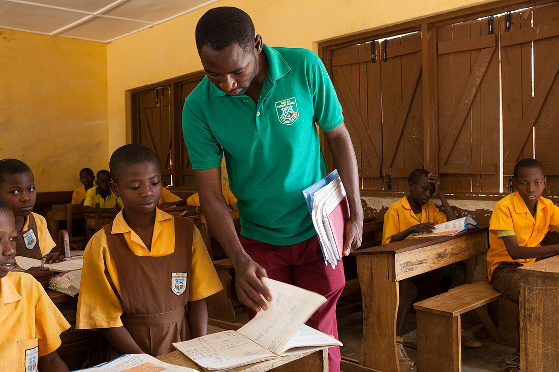 Teacher guiding students in a Ghanaian classroom